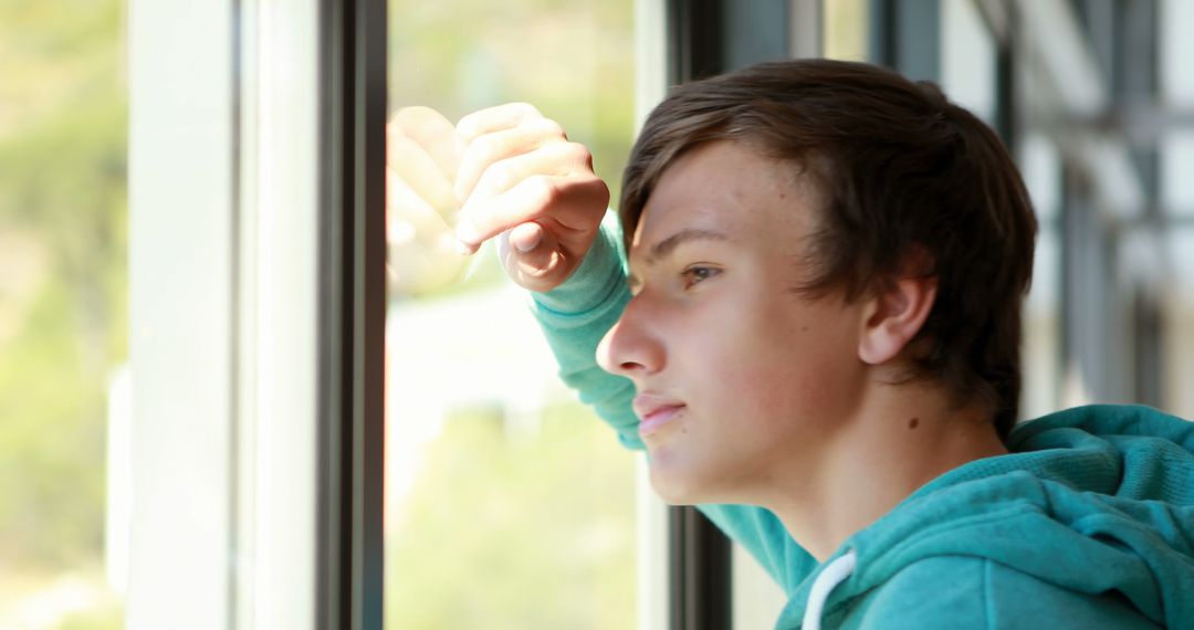 Teenage Boy Reflecting By Window, Wearing Green Hoodie - Free Images, Stock Photos and Pictures on Pikwizard.com