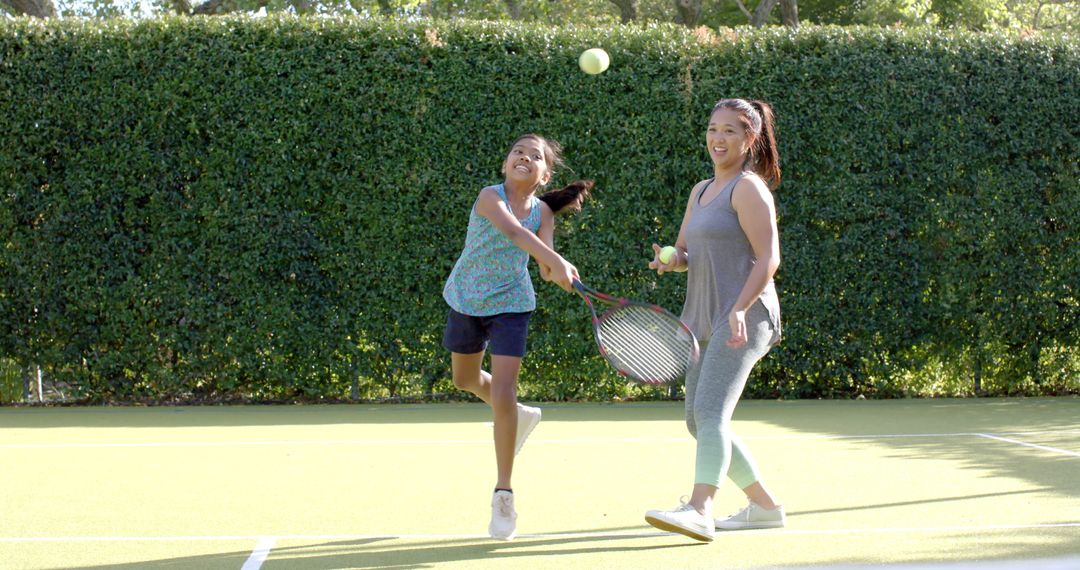 Mother and Child Playing Tennis on Sunny Day