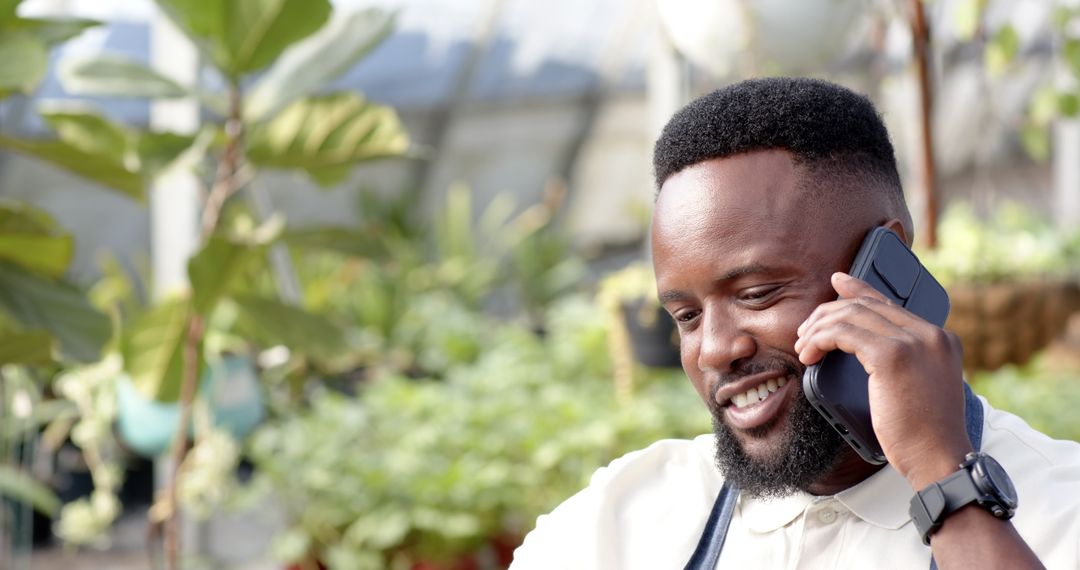 Smiling Horticulturist Talking on Smartphone in Greenhouse