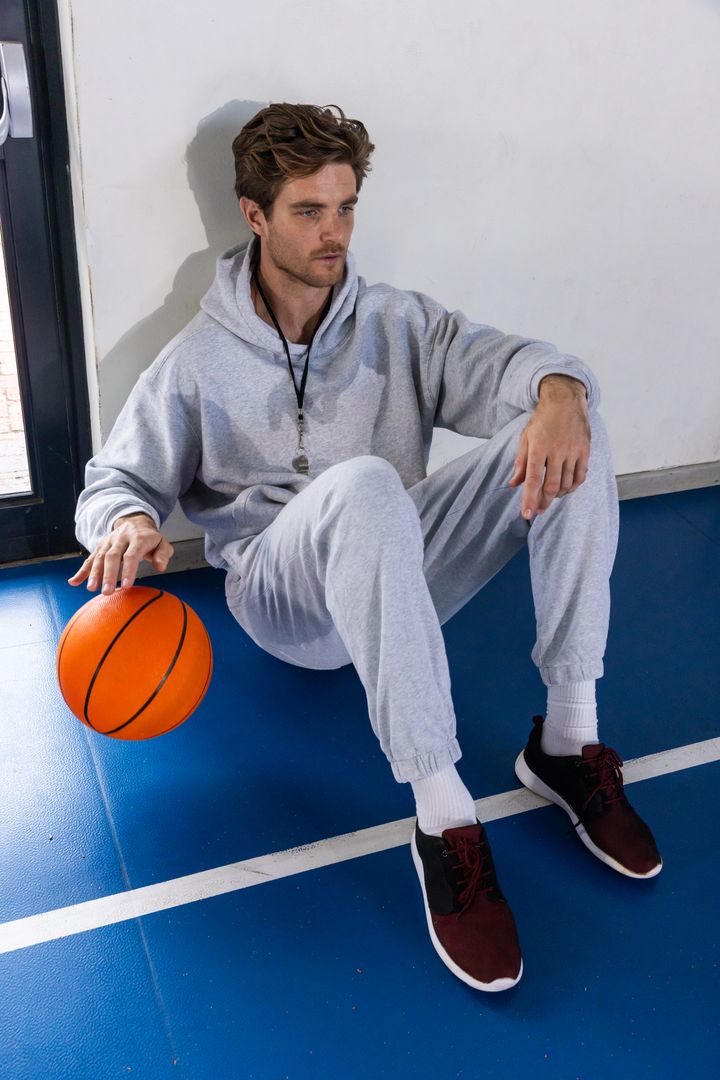 Athletic Man Relaxing on Basketball Court in Urban Activewear