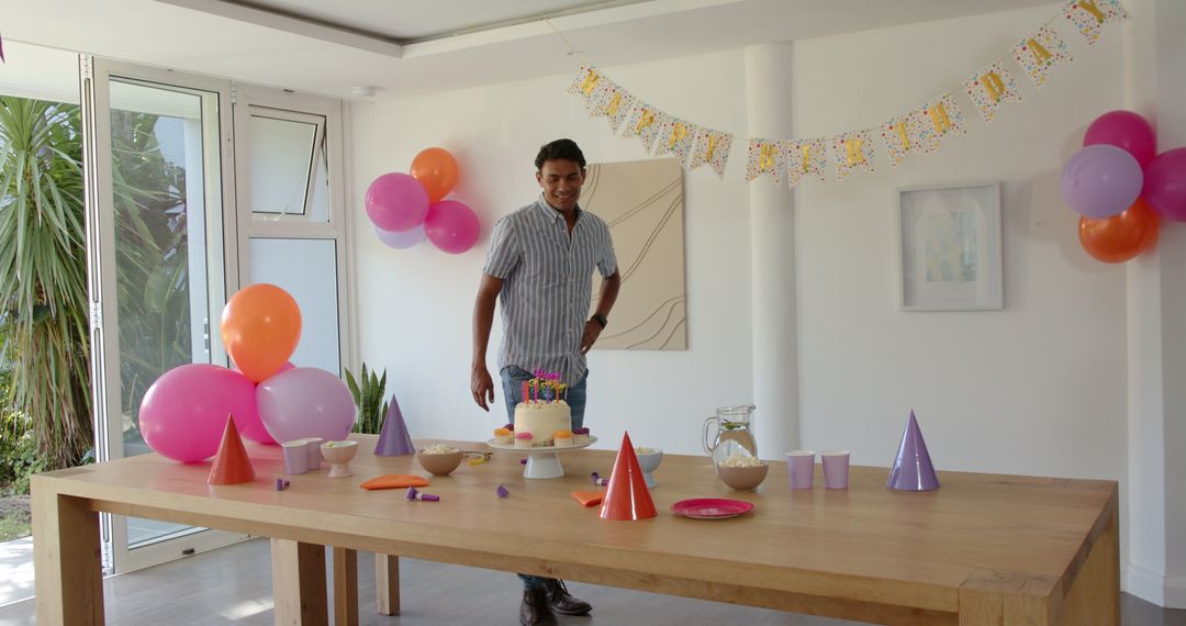 Man Decorating Birthday Party Table with Cake and Balloons Indoors