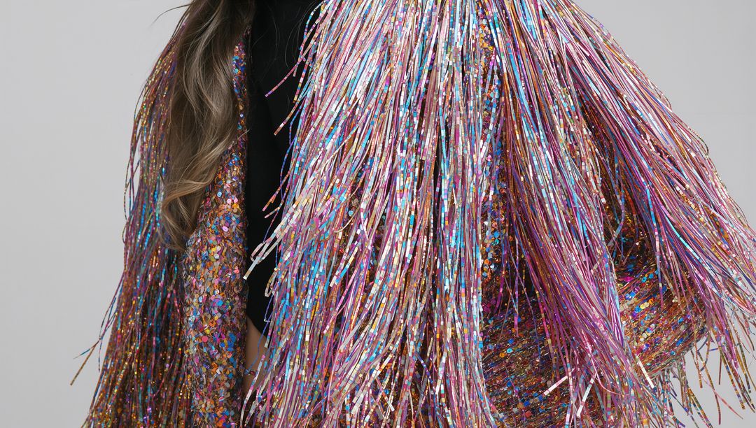 Model wearing iridescent metallic fringe jacket sparkling with multicolor tinsel