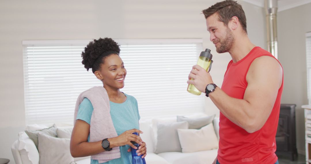 Image of happy diverse couple drinking water after training at home - Free Images, Stock Photos and Pictures on Pikwizard.com
