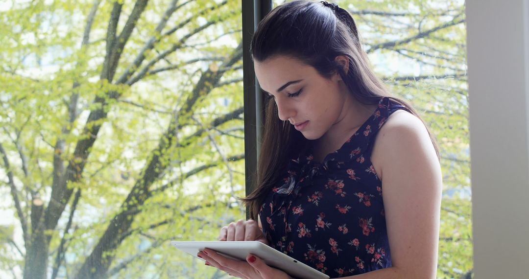 Young Woman Using Tablet by Large Window with Nature View - Free Images, Stock Photos and Pictures on Pikwizard.com