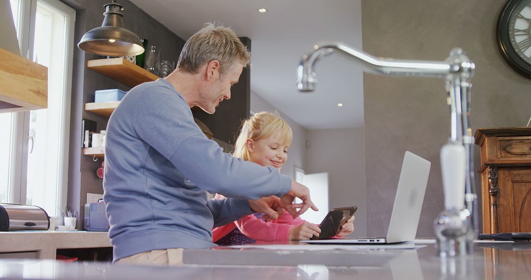 Father and daughter using digital devices in modern kitchen - Free Images, Stock Photos and Pictures on Pikwizard.com