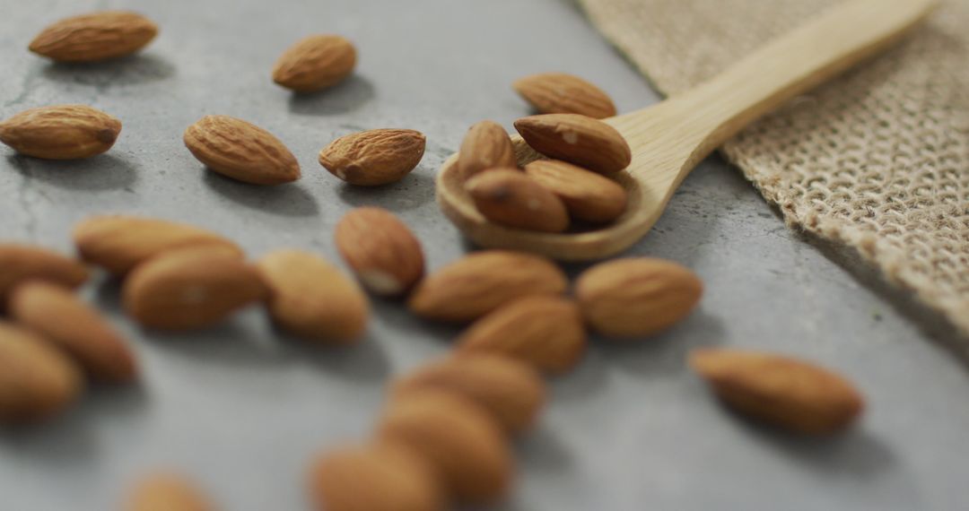 Almonds Scattered with Wooden Spoon on Stone Countertop