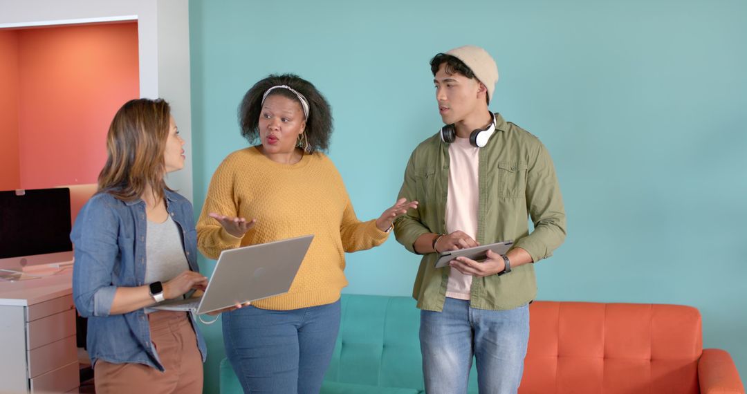 Diverse team discussing project in colorful coworking space with laptop and tablet