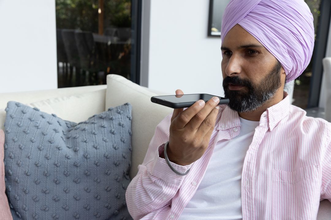 Man in Turban Using Smartphone Voice Assistant on Sofa