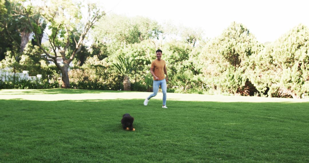 Man Playing Fetch with Black Puppy on Lush Lawn Outdoors