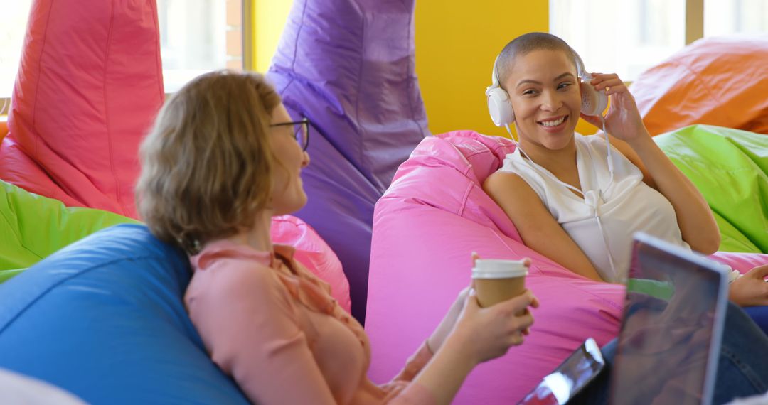 Young Women Enjoy Relaxing Coffee and Music on Colorful Bean Bags - Free Images, Stock Photos and Pictures on Pikwizard.com