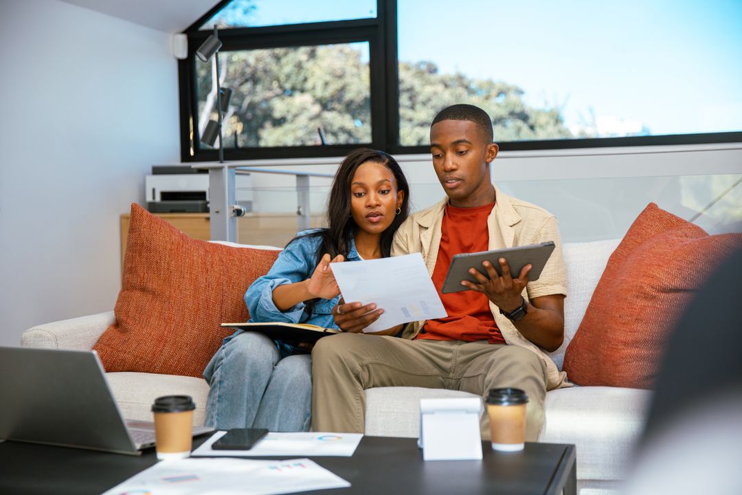 Couple Reviewing Documents at Home with Tablet and Coffee