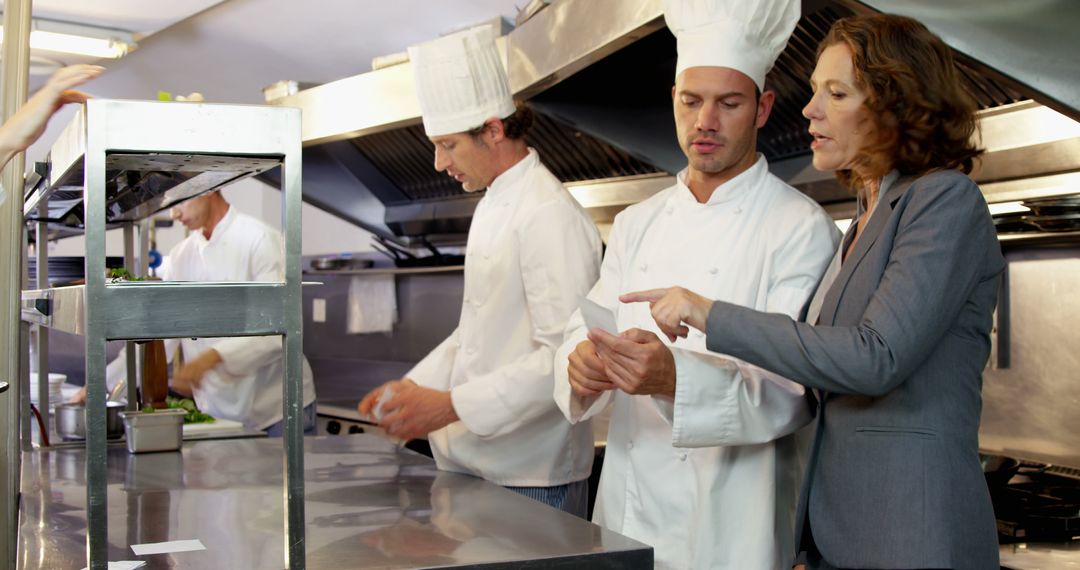 Restaurant Manager Discussing Menu with Chefs in Professional Kitchen - Free Images, Stock Photos and Pictures on Pikwizard.com