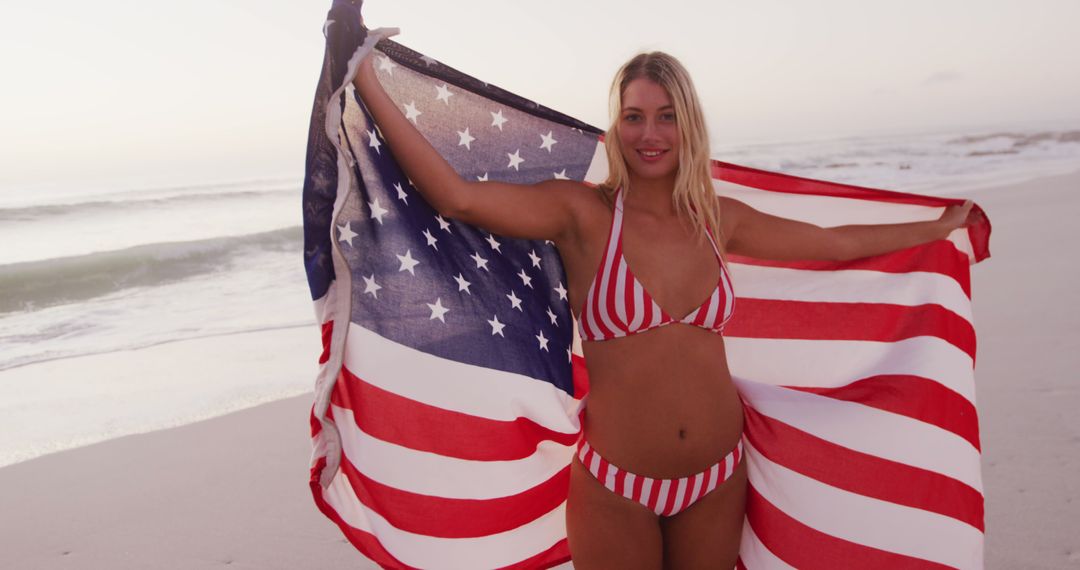 Portrait of happy caucasian woman holding flag of usa and smiling on beach - Free Images, Stock Photos and Pictures on Pikwizard.com