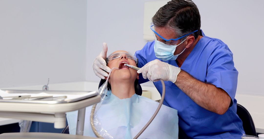 Dentist Treating Female Patient with Dental Equipment in Clinic - Free Images, Stock Photos and Pictures on Pikwizard.com