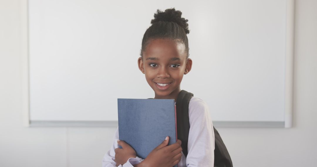Smiling African American Girl Holding Notebook in Classroom Environment