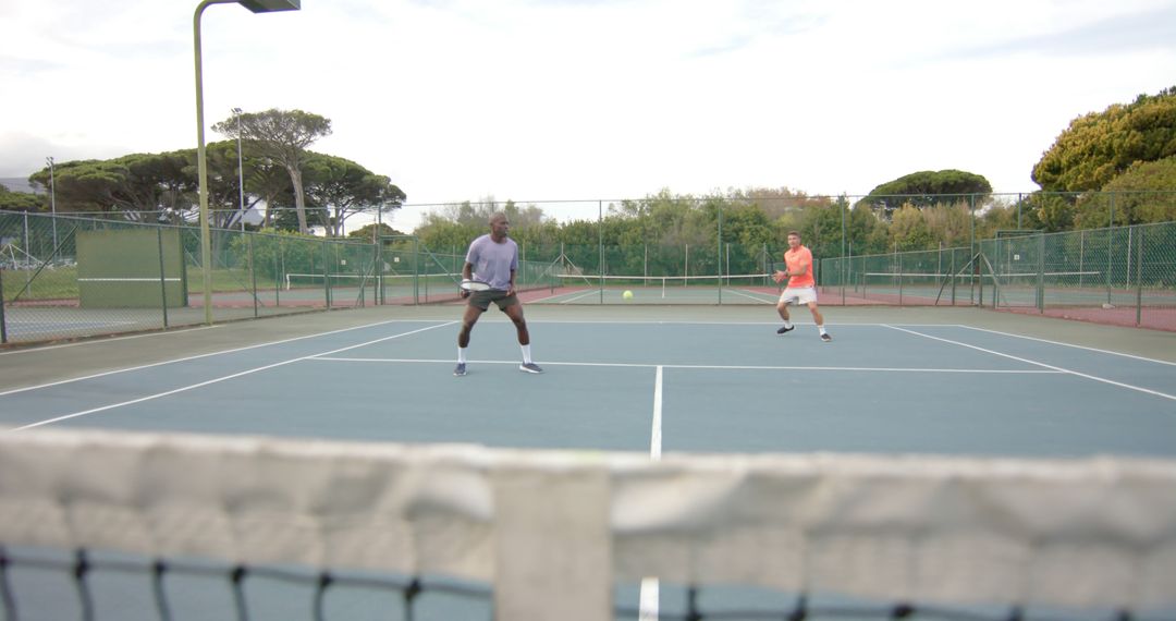 Two Men Playing Doubles Tennis Match on Outdoor Court - Free Images, Stock Photos and Pictures on Pikwizard.com