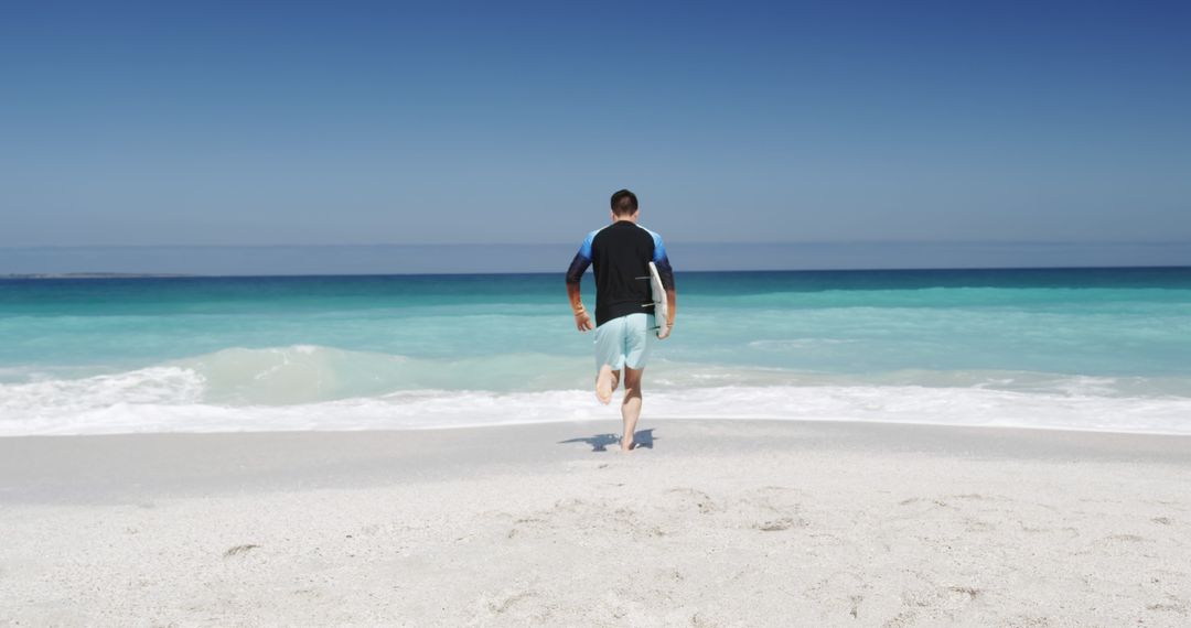 Man Walking on Sandy Beach towards Ocean under Clear Blue Sky - Free Images, Stock Photos and Pictures on Pikwizard.com