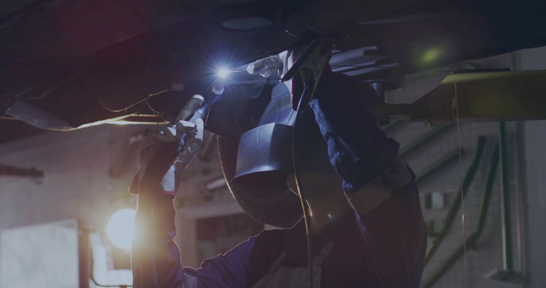 Welder in Action Repairing Vehicle Chassis in Workshop