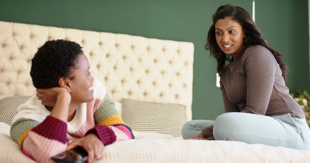 Diverse Friends Chatting Casually on Bed with Smartphone