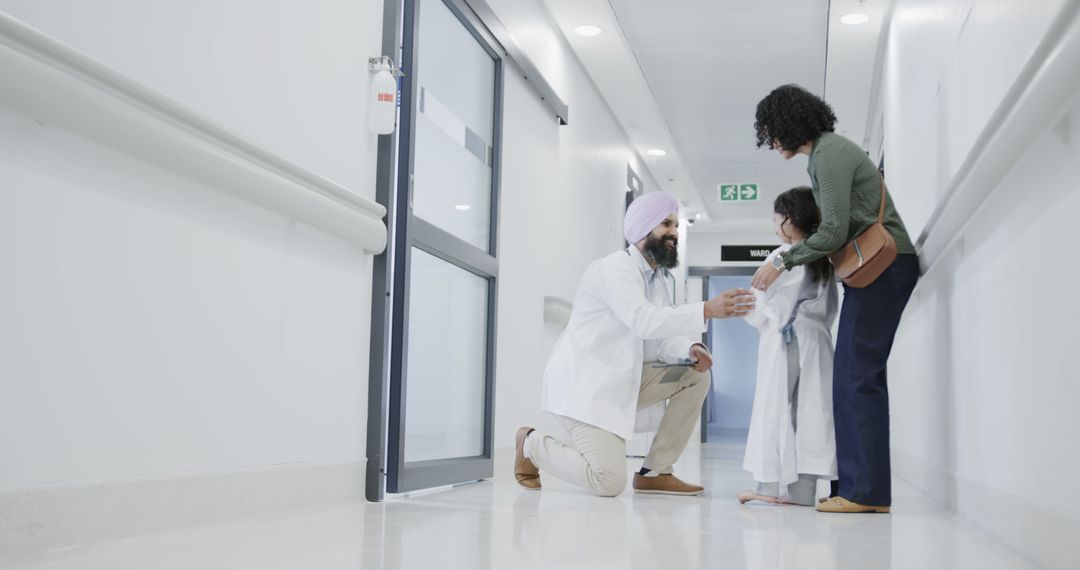 Doctor Greeting Young Patient and Mother in Hospital Corridor - Free Images, Stock Photos and Pictures on Pikwizard.com