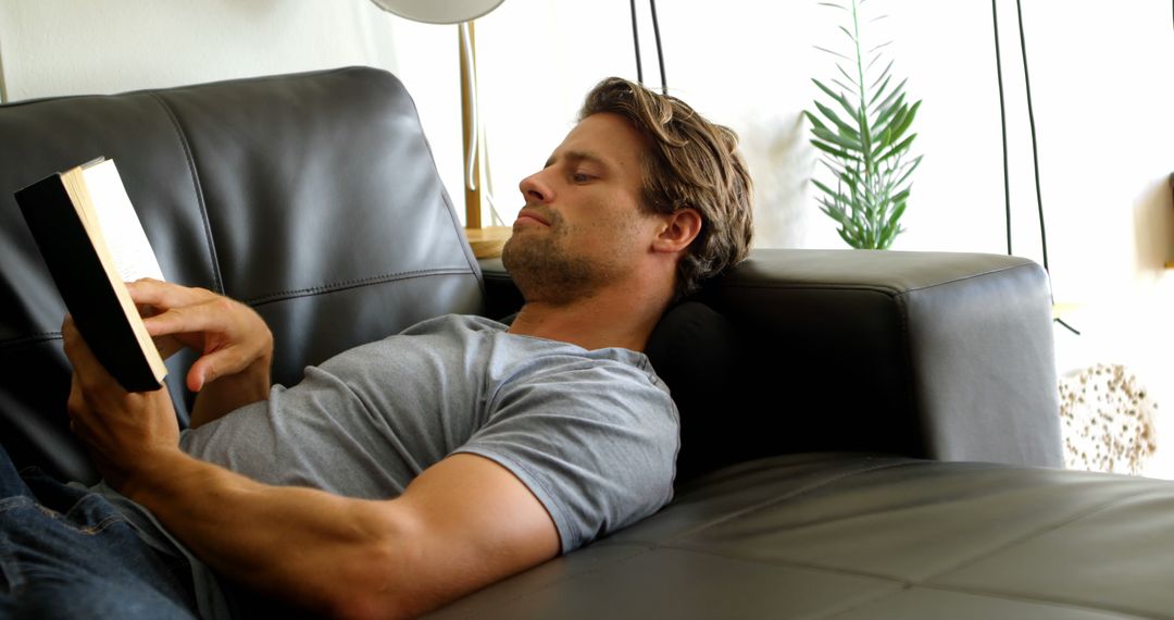 Man Relaxing on Sofa Reading a Book in Modern Living Room - Free Images, Stock Photos and Pictures on Pikwizard.com