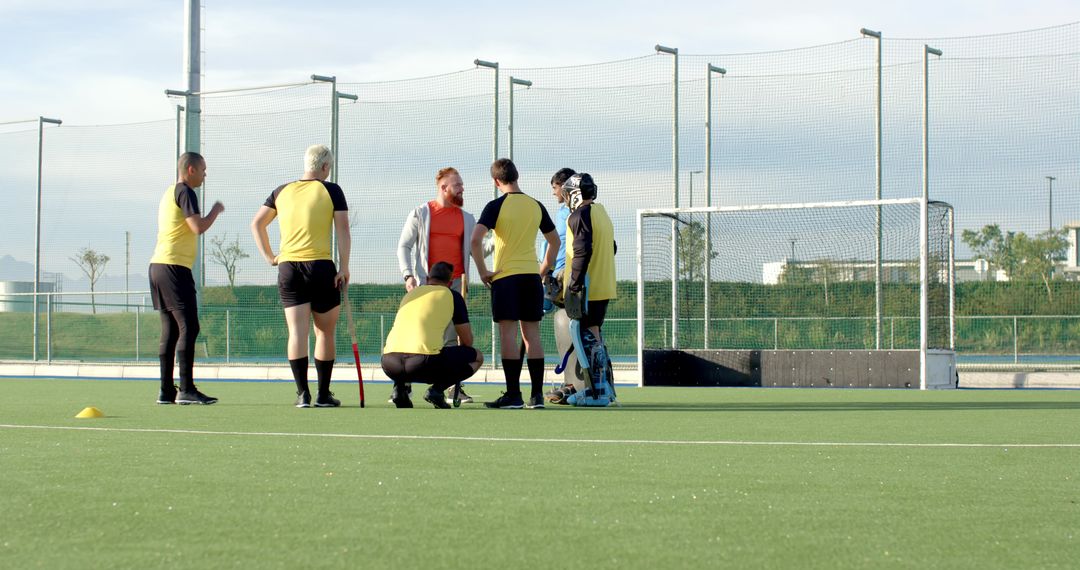 Field Hockey Team Strategizing with Coach on Practice Field