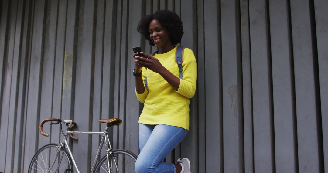 Smiling Young Woman Texting on Smartphone with Bike Against Wall - Free Images, Stock Photos and Pictures on Pikwizard.com