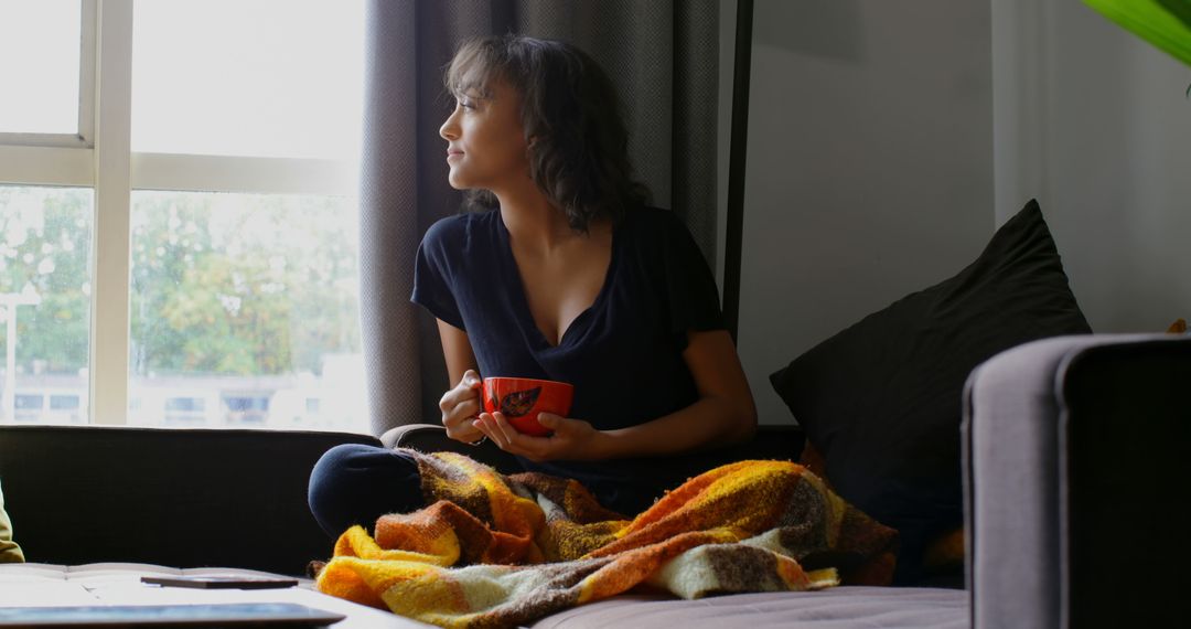 Woman Sitting on Couch with Coffee Looking Out Window - Free Images, Stock Photos and Pictures on Pikwizard.com