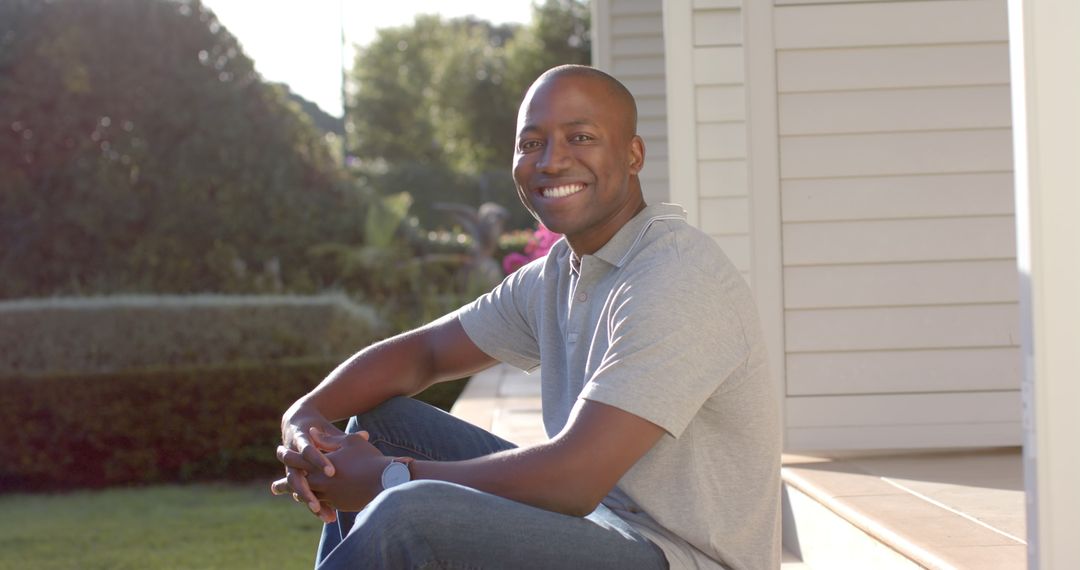 Smiling Man Relaxing on Porch Steps in Sunny Setting