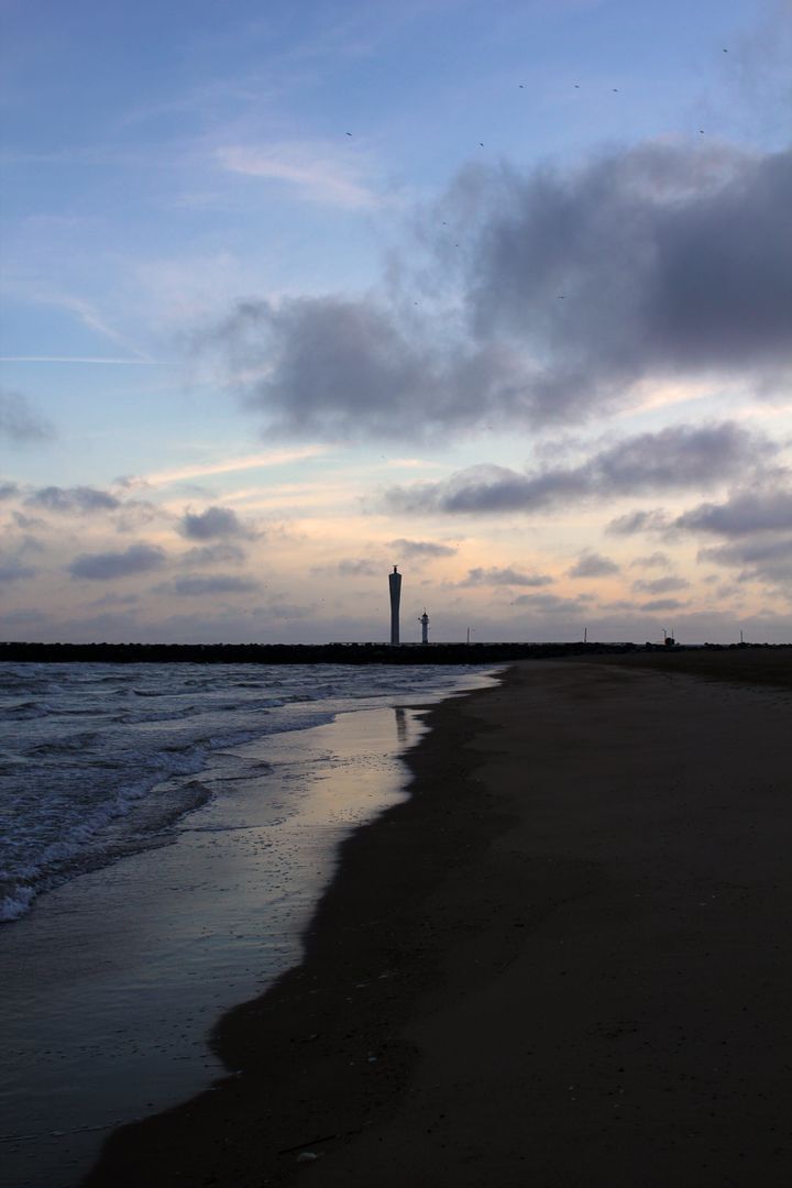 Peaceful Beach Shoreline at Sunset with Distant Tower - Free Images, Stock Photos and Pictures on Pikwizard.com