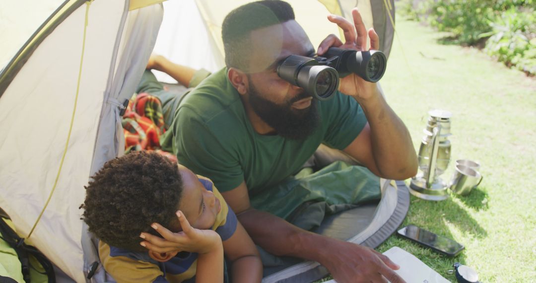 Father and Son Camping in Tent with Binoculars and Laptop - Free Images, Stock Photos and Pictures on Pikwizard.com