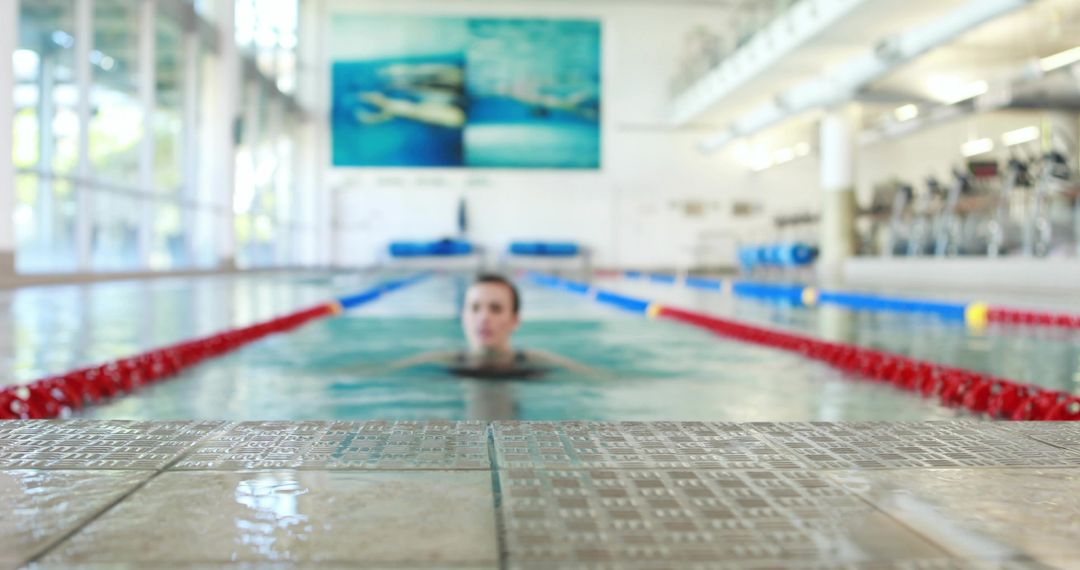 Female athlete treading water facing camera in indoor lap pool with red lane ropes