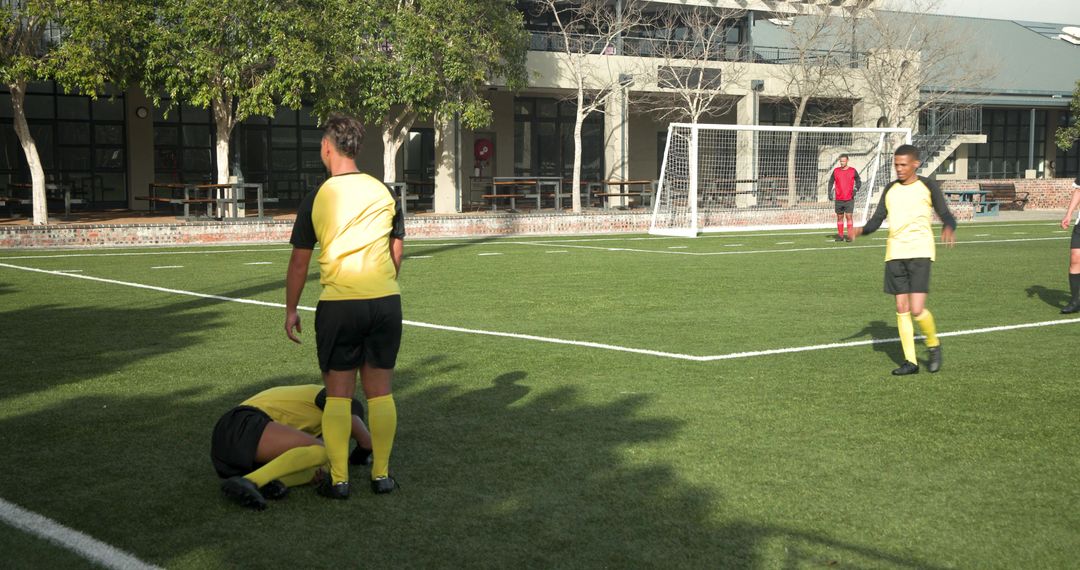 Caring Soccer Players Supporting Injured Teammate on Field
