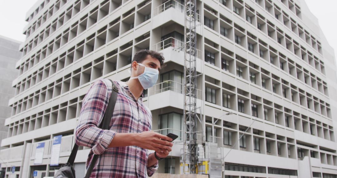 Man Wearing Face Mask Holding Smartphone Near Building - Free Images, Stock Photos and Pictures on Pikwizard.com