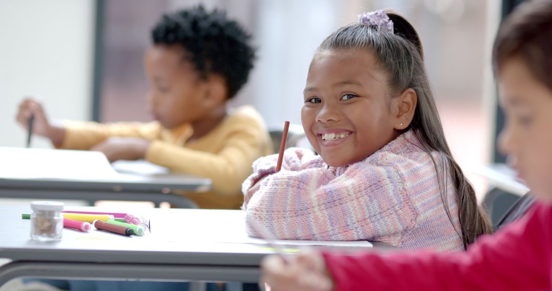 Smiling Schoolgirl Holding Pencil During Classroom Lesson