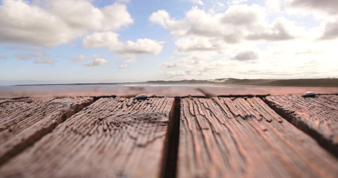 Bird Flying Above Wooden Plank Against Cloudy Sky