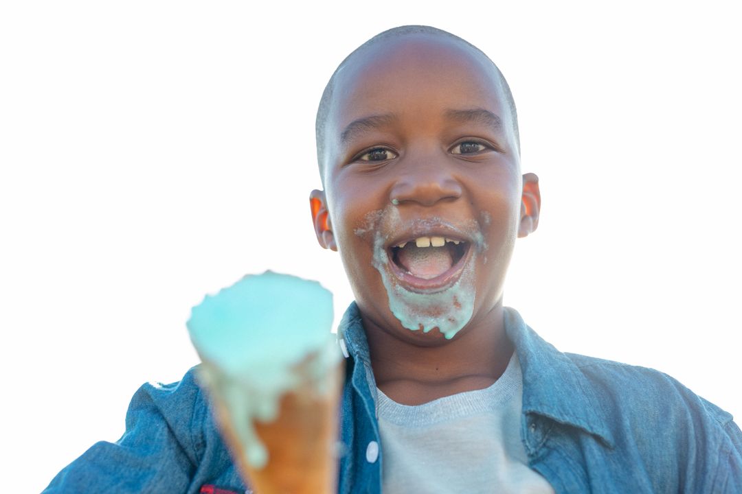 Portrait of cheerful african american boy with messy mouth holding melting ice cream on sunny day - Free Images, Stock Photos and Pictures on Pikwizard.com