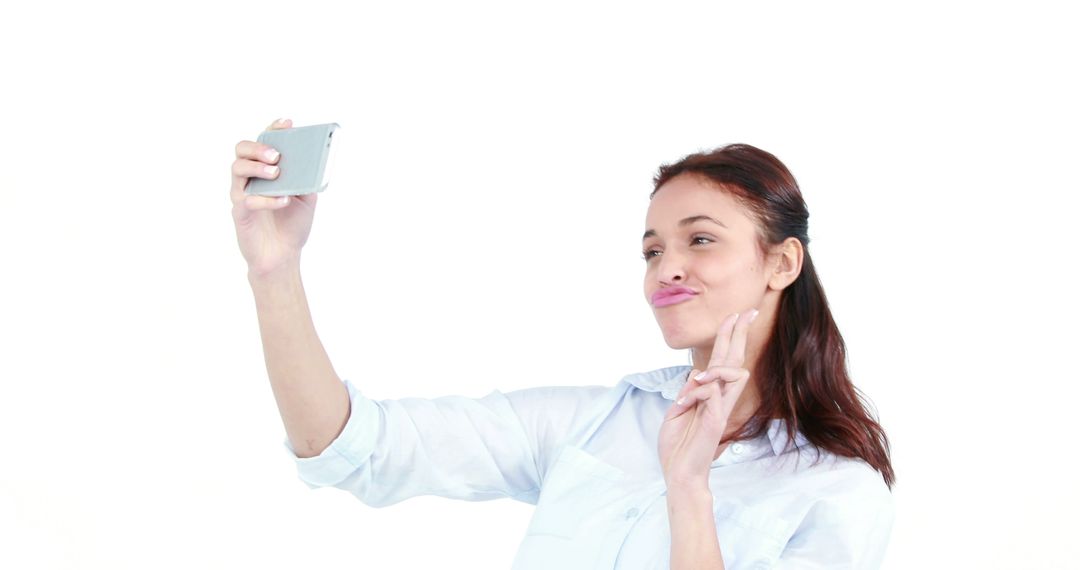 Playful Young Woman Taking Selfie on White Background - Free Images, Stock Photos and Pictures on Pikwizard.com