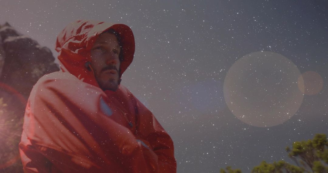 Man in Red Parka Exploring at Rocky Ridge Under Starry Sky