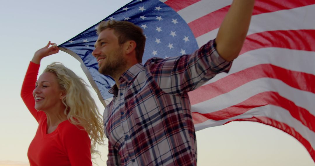 Joyful Couple Running with American Flag at Beach