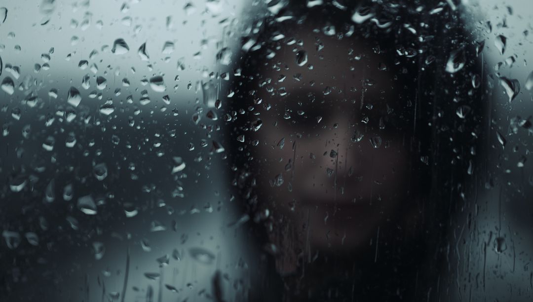 Moody Silhouette of Woman Behind Rain-Soaked Window