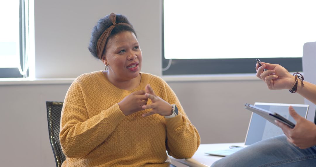 African American woman gesturing and explaining during collaborative team meeting in office