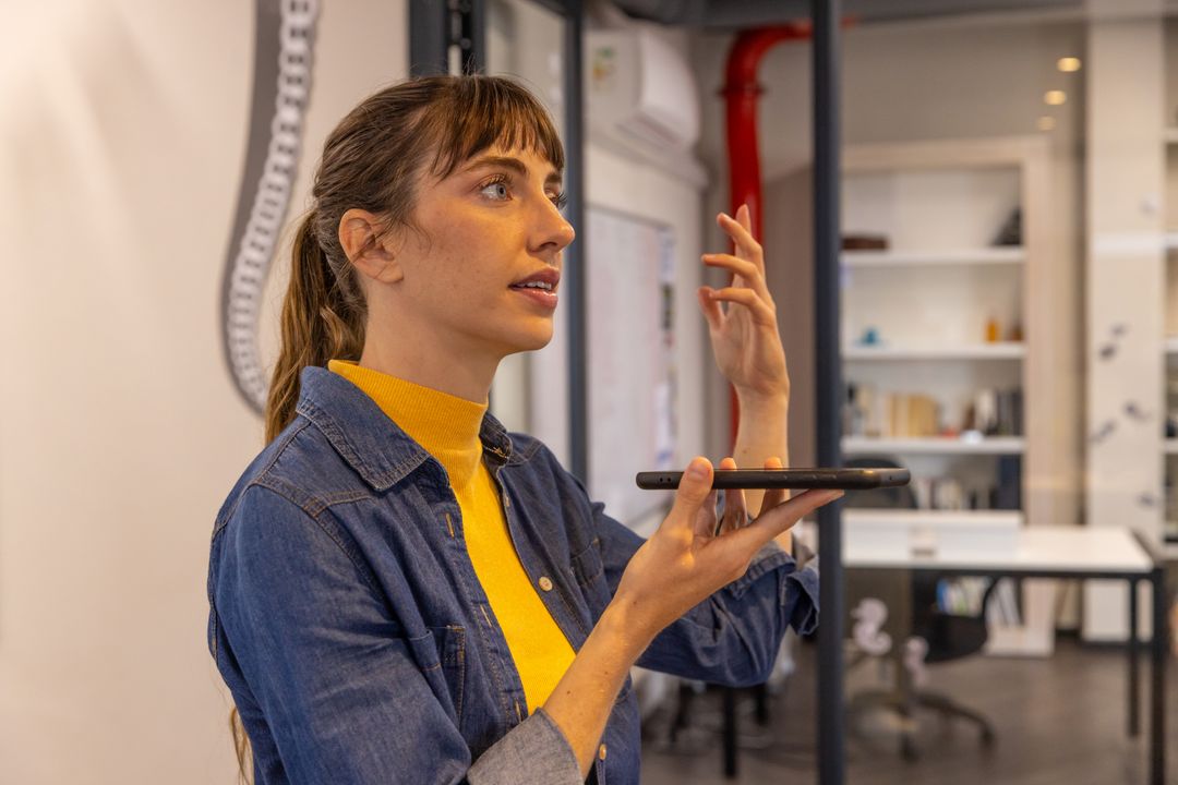 Mid Adult Woman Using Voice Command on Smartphone in Modern Office