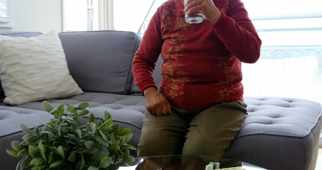 Elderly Woman Drinking Water and Relaxing on Sofa in Living Room - Free Images, Stock Photos and Pictures on Pikwizard.com