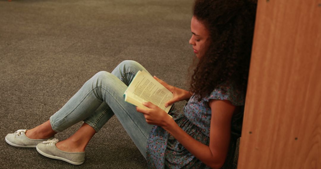 Young African American woman reading book on floor in cozy space - Free Images, Stock Photos and Pictures on Pikwizard.com