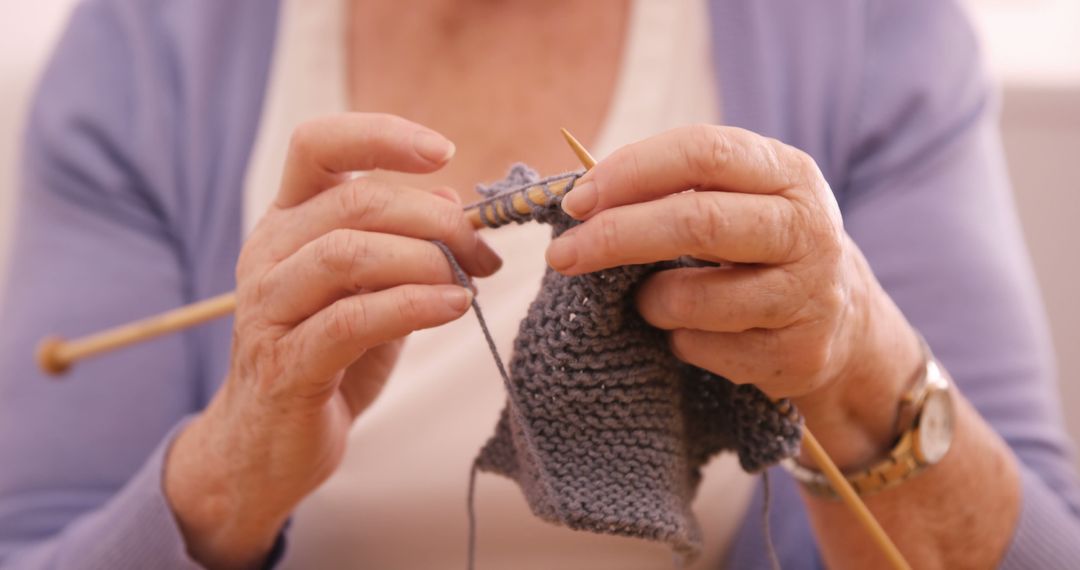 Senior Woman's Hands Knitting Gray Yarn for Relaxation and Craft