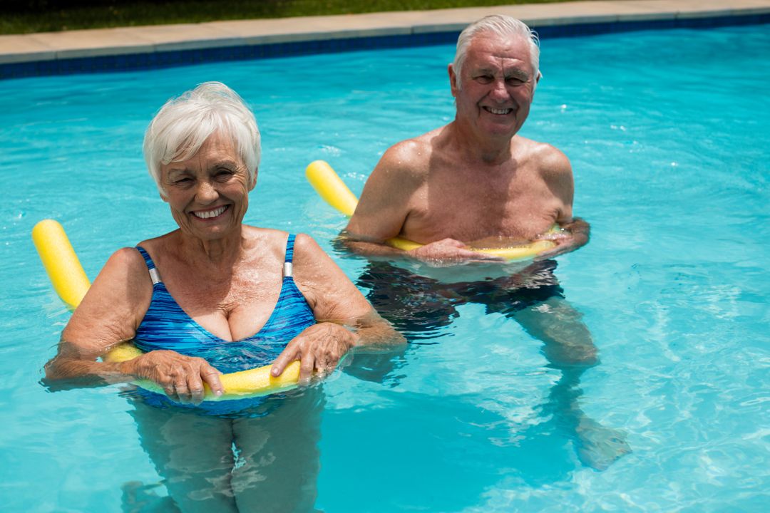 Senior couple swimming in the pool with inflatable tubes - Free Images, Stock Photos and Pictures on Pikwizard.com