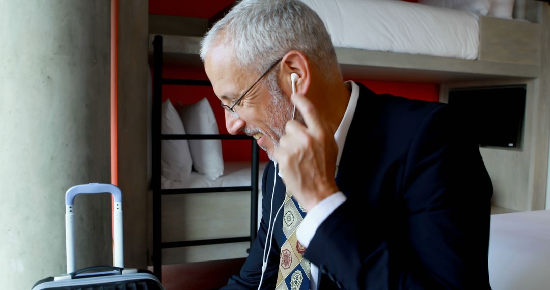 Businessman listening to music with earbuds in modern hotel room - Free Images, Stock Photos and Pictures on Pikwizard.com