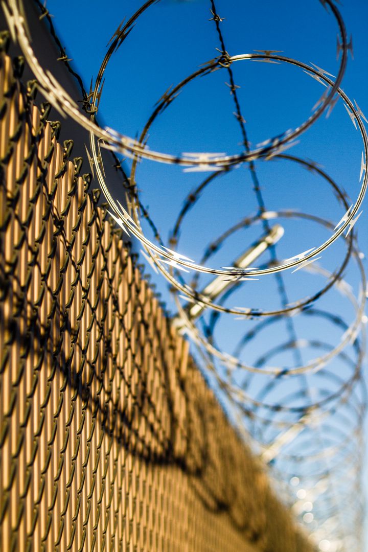 Barbed Wire Fence Under Clear Blue Sky, Symbolizing Security and Boundaries - Free Images, Stock Photos and Pictures on Pikwizard.com