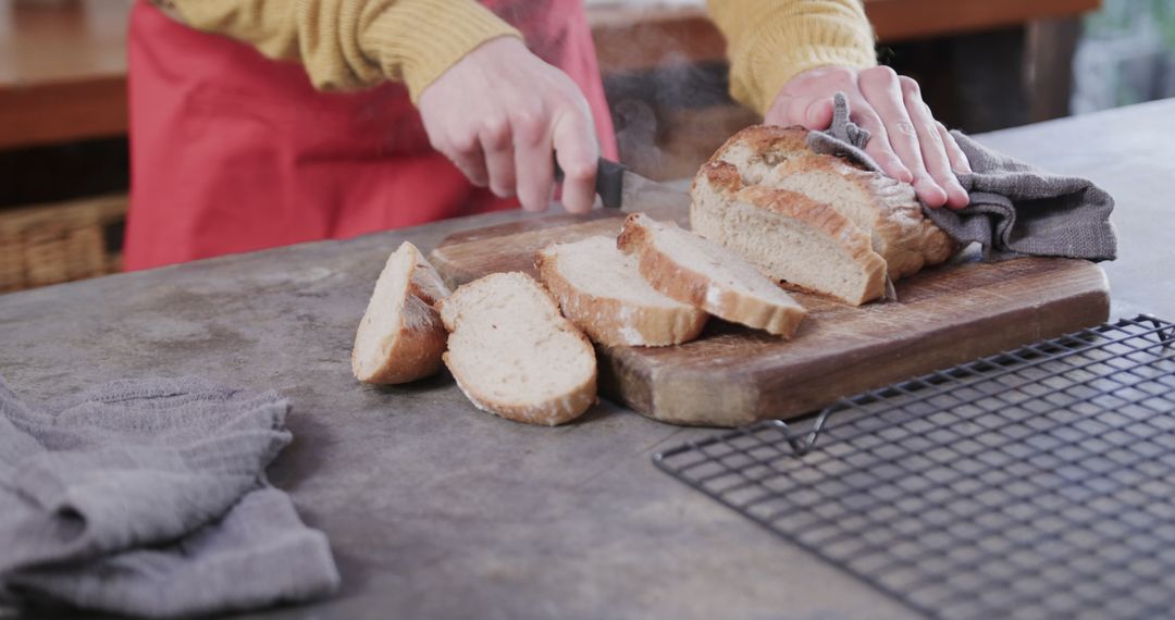 Person Slicing Freshly Baked Rustic Bread in Kitchen - Free Images, Stock Photos and Pictures on Pikwizard.com